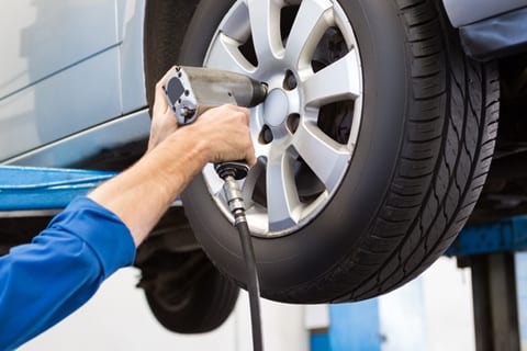 Auto technician performing a wheel alignment on a vehicle inside Burt Brothers service center