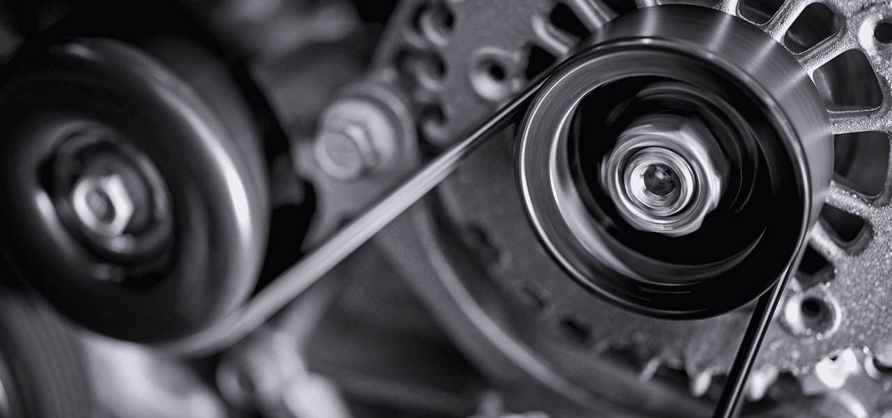 Close-up view of a car alternator showing its metal housing and connected to the serpentine belt.