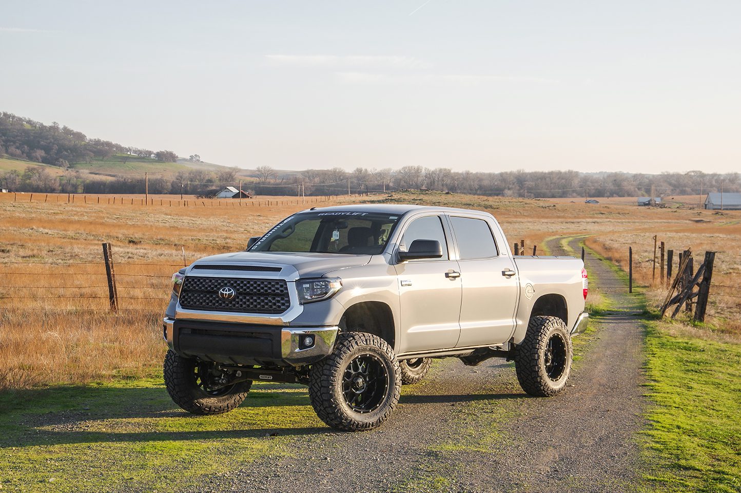 Front view of a gold Toyota Tundra parked on a sunlit road with rugged terrain in the background, highlighting strength and performance for Burt Brothers’ gasoline octane guide.