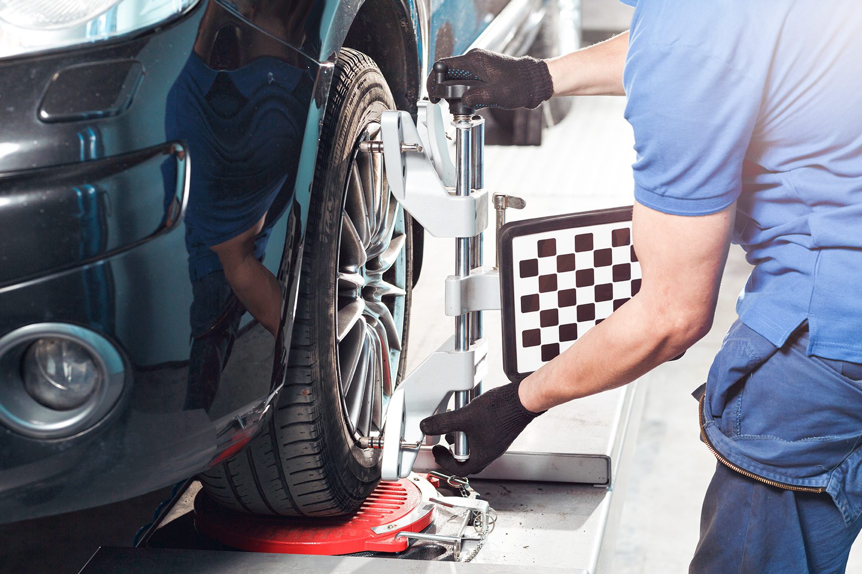 Technician performing a wheel alignment on a vehicle inside a Burt Brothers service bay.