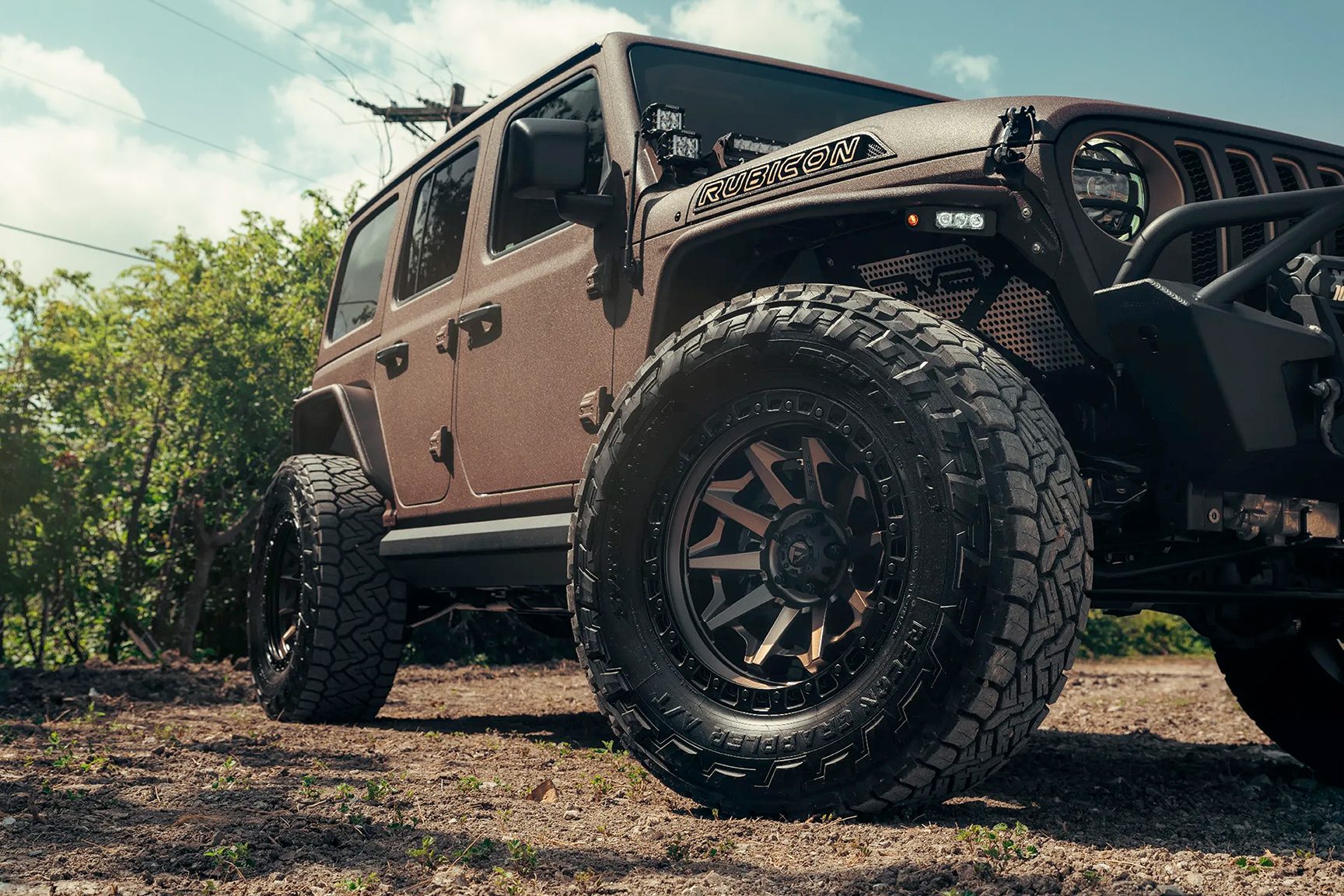 Close-up view of custom wheels and tires installed on a rugged Jeep Rubicon at Burt Brothers.