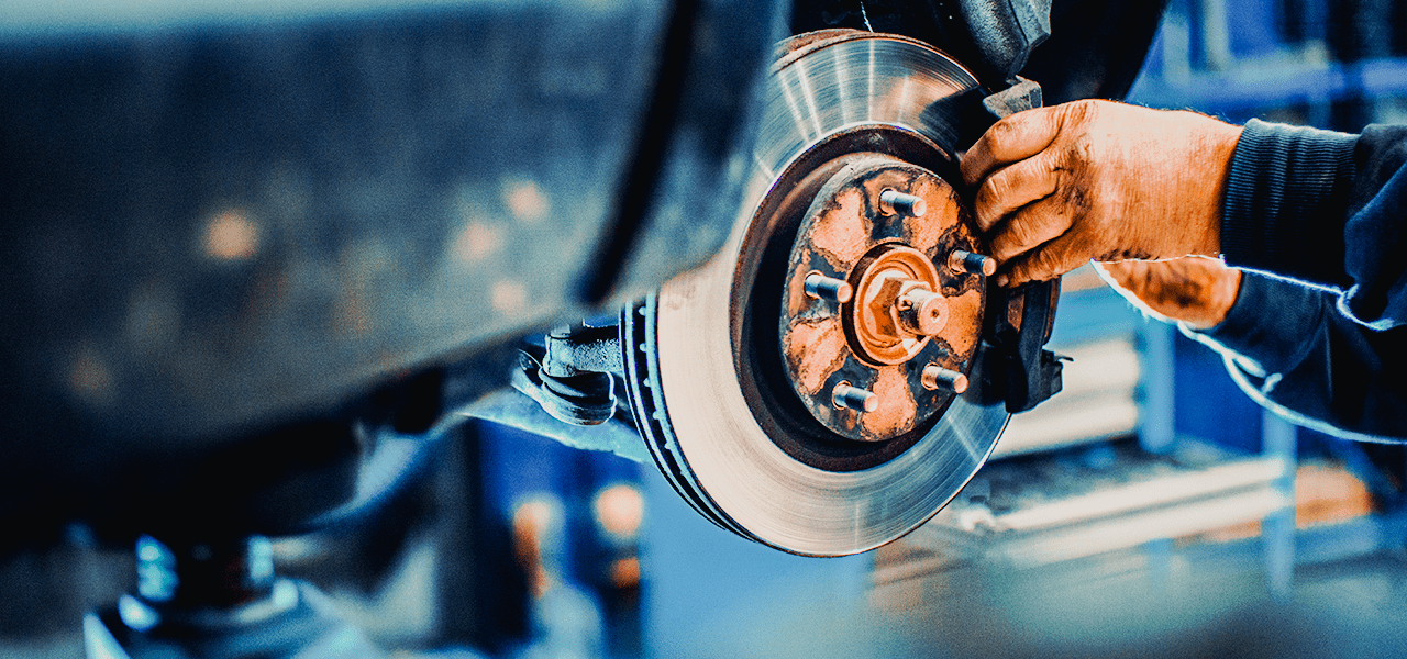 Burt Brothers technician installing new brakes pads on a raised vehicle.
