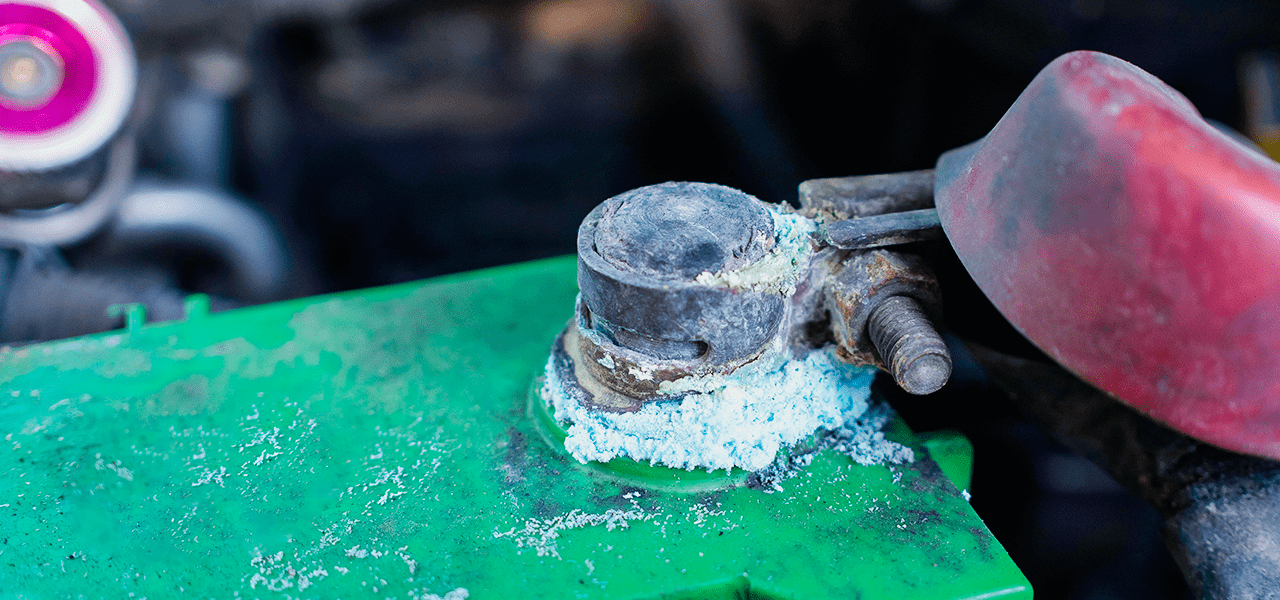 Close-up of a car battery with visible corrosion around the terminals.