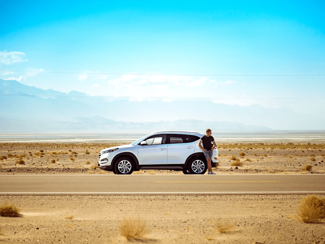 Picture of a man leaning on a parked SUV on the side of the Utah highway